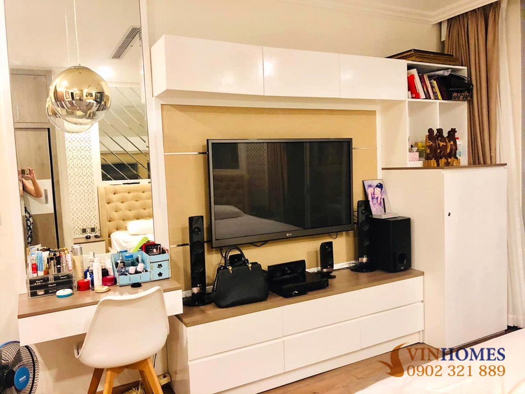 Nội thất thực tế bên trong căn hộ với phòng ngủ và khu kệ tivi thiết kế hiện đại, tông màu trắng gỗ ấm áp.