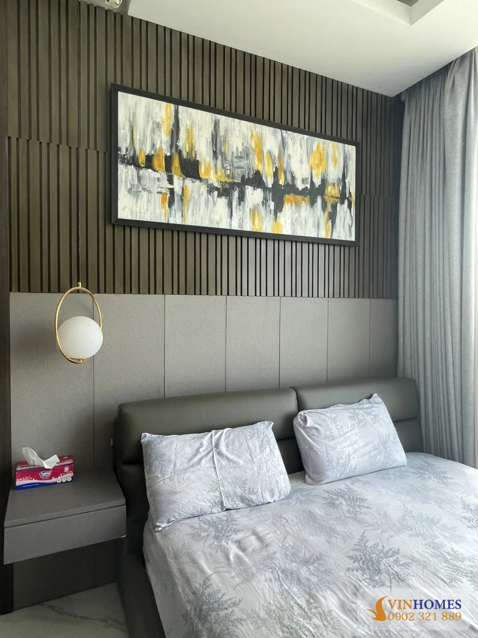 Phòng ngủ căn hộ Vinhomes Central Park với giường lớn, vách gỗ trang trí và tranh treo tường